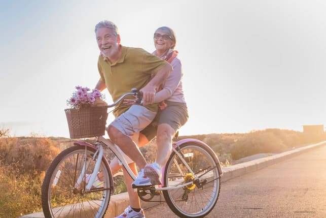 a senior couple riding a bike together and having fun