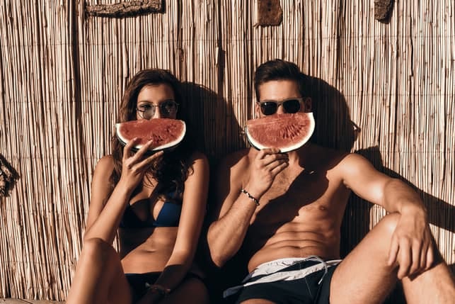 a sporty couple eating watermelon together