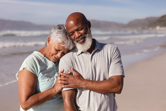 a couple of black seniors having a walk on the beach