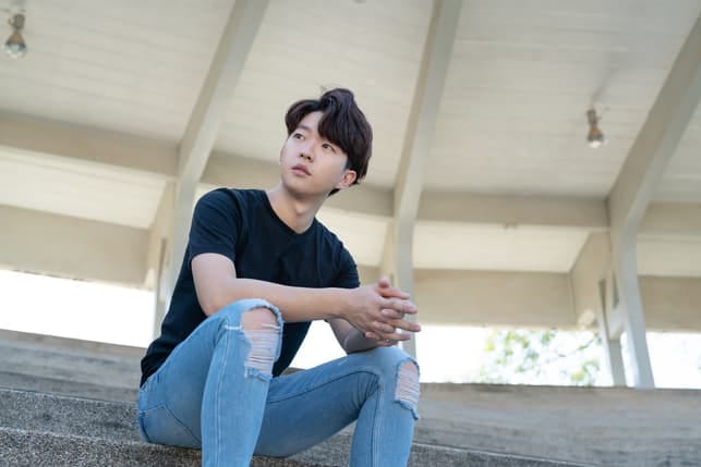 a young asian man relaxing outside