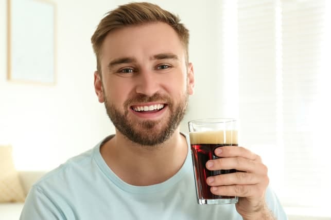 a man with a glass of soda posing and smiling