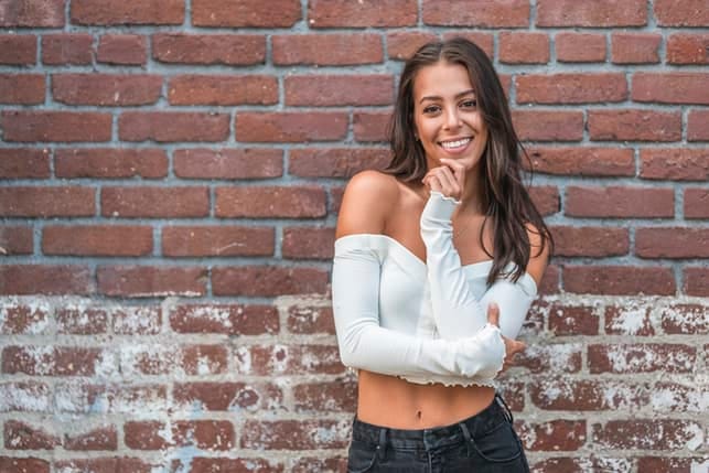 a young woman in white is posing outdoors
