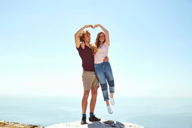 a couple making a heart sign with their hands
