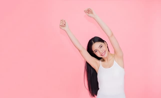 an attractive asian woman is posing on a pink background