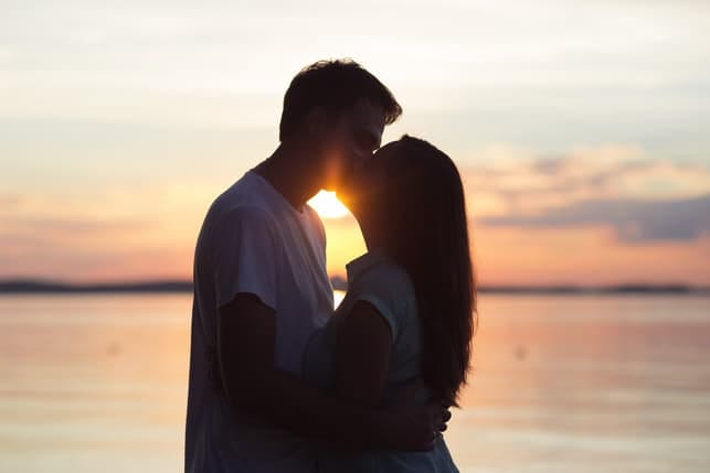 a young couple kissing together on a beach