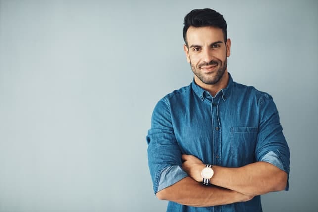 an attractive man in a blue shirt posing indoors