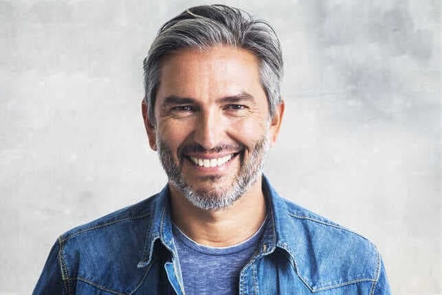 a mature man is a blue shirt is smiling