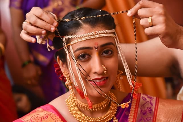 an indian woman getting dressed in traditional clothing