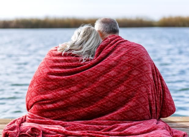 a senior couple having a nice day under a blanket on a beach