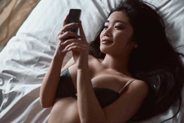 an asian woman in underwear is checking her phone