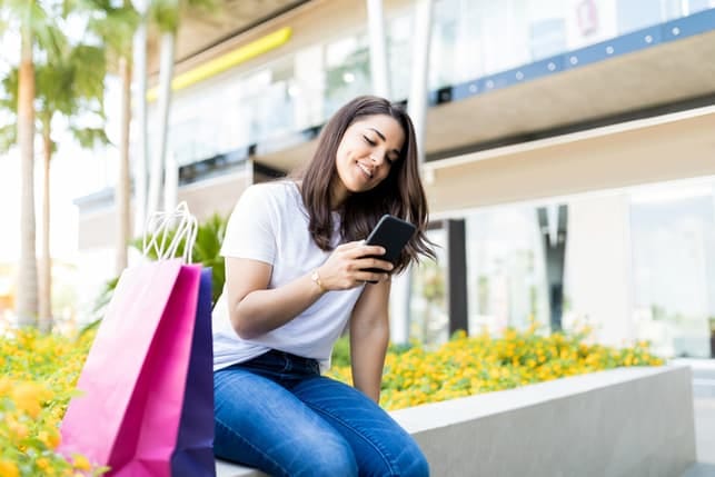 a woman using her smartphone after shopping