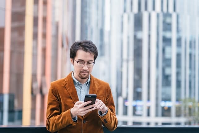 a serious Asian man using his smartphone
