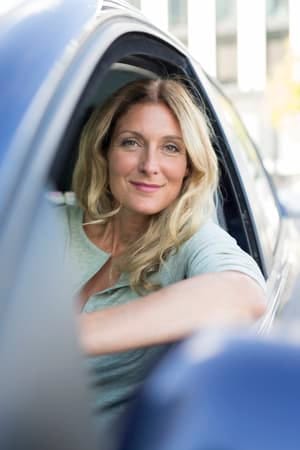 a blonde woman over 45 posing while sitting in her car