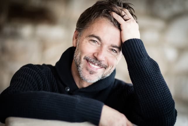 a portrait of an adult bearded man smiling