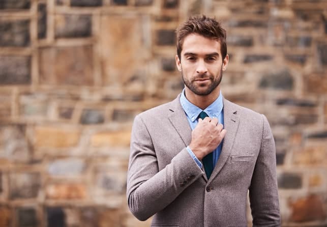 a guy wearing suit posing outdoors