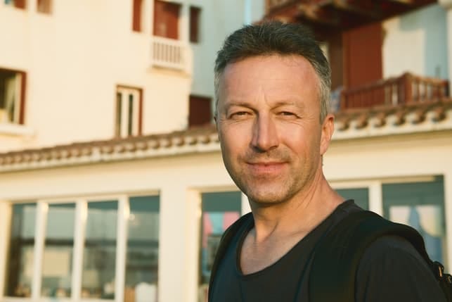 an attractive middle-aged man is posing outdoors