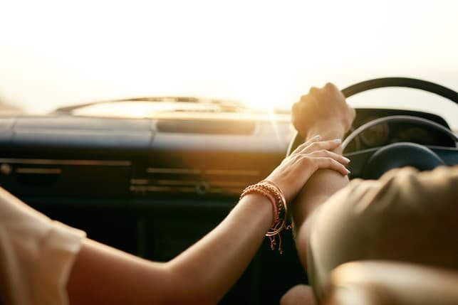 a couple holding hands while driving