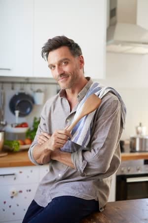 an attractive middle-aged man posing while cooking