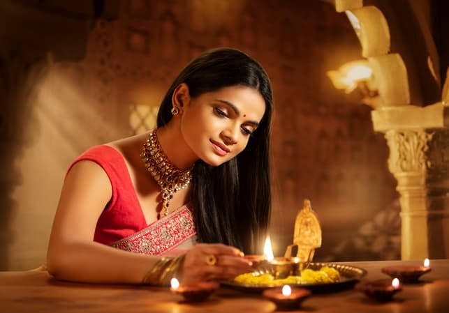 a beautiful indian girl lighting up a candle