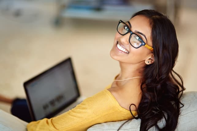 a young Indian girl in yellow working on her laptop