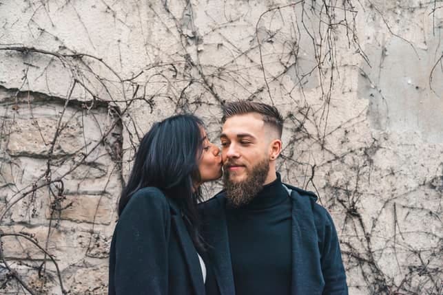 a mixed couple kissing outdoors