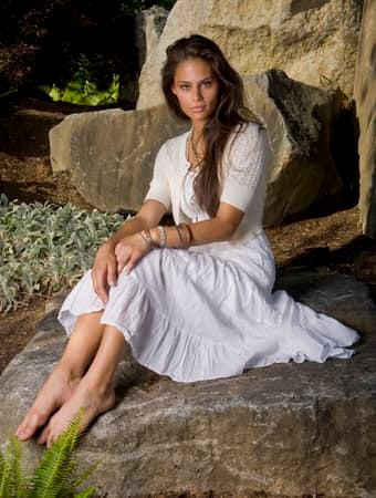a portrait of a woman in a white dress posing outdoors